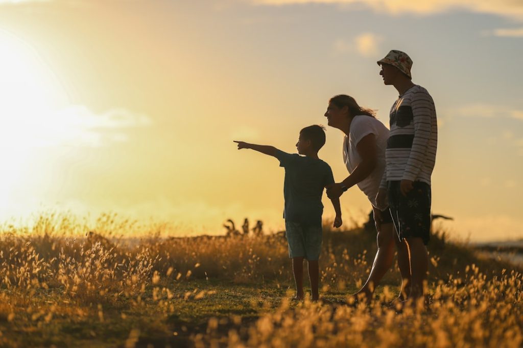 man, woman, and son walking in a lovely field at sunset