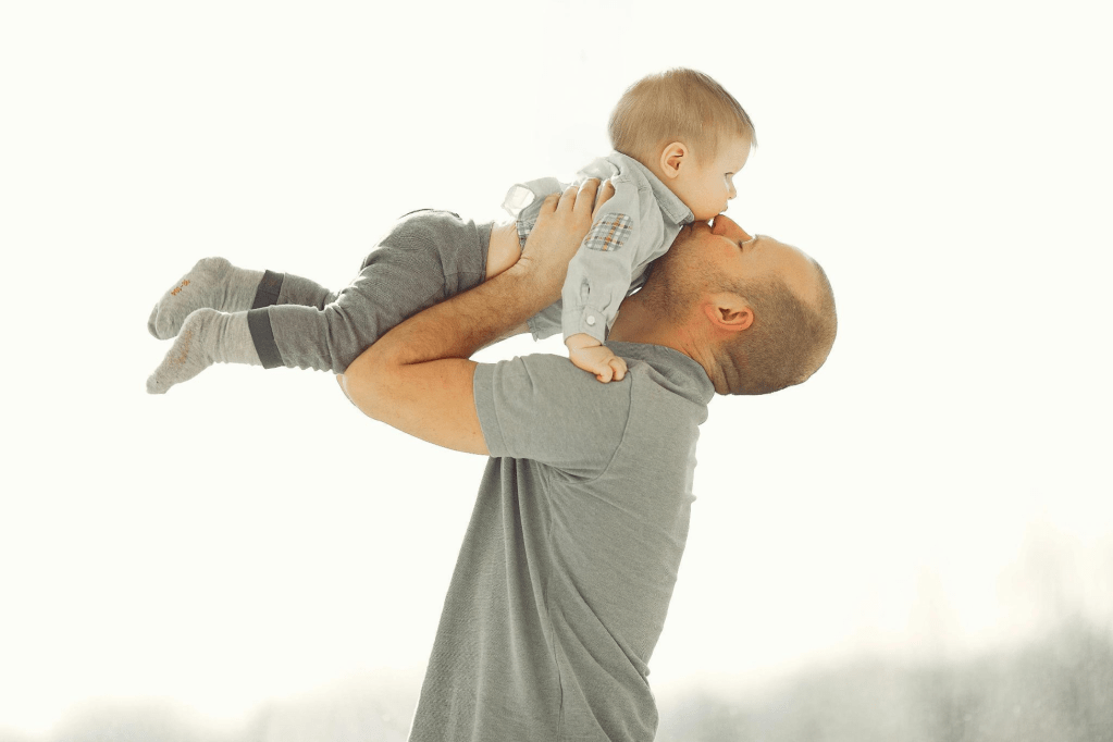 Father holding baby up over his head with affection