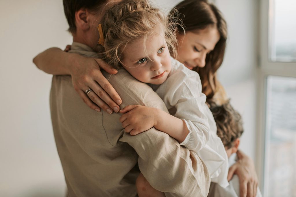 father holding young daughter and mother with arm around son