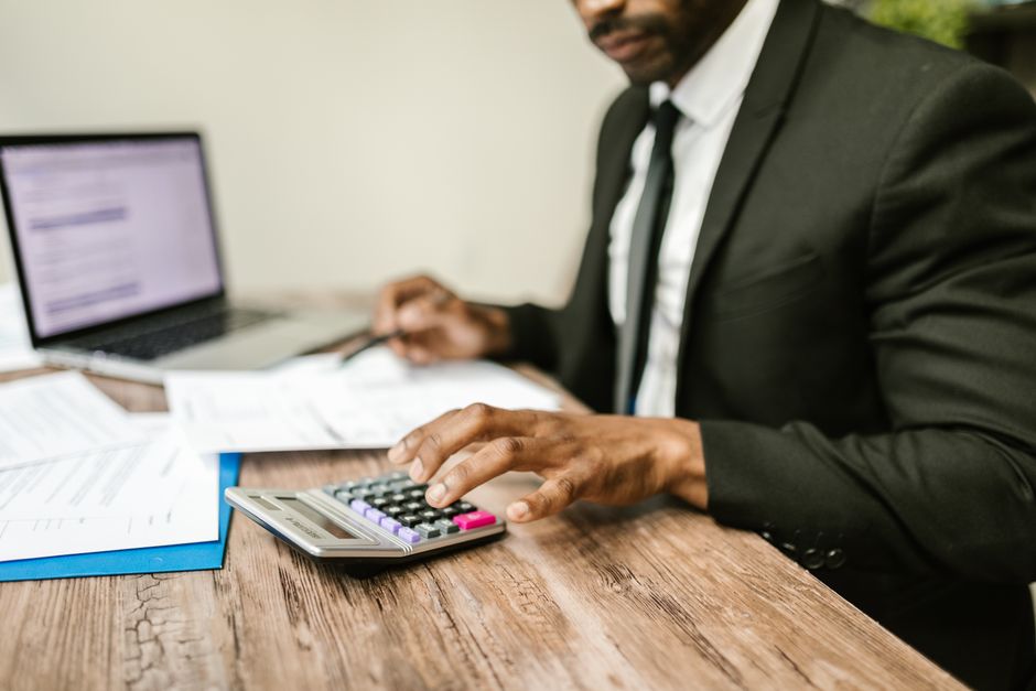 pexels-photo-7821716-7821716 A businessman in a black suit using a calculator at a desk to represent spousal support